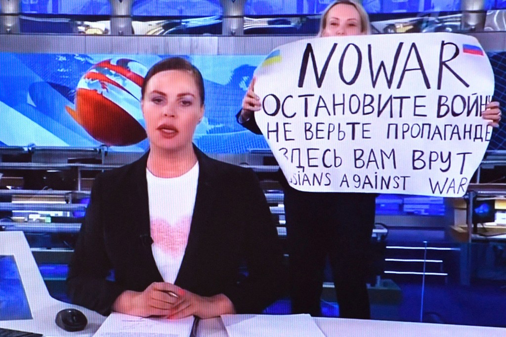امرأة تنظر إلى شاشة كمبيوتر تشاهد موظفًا روسيًا معارضًا في القناة الأولى يدخل استوديو أوستانكينو التلفزيوني على الهواء خلال بث الأخبار المسائية الأكثر مشاهدة في روسيا.