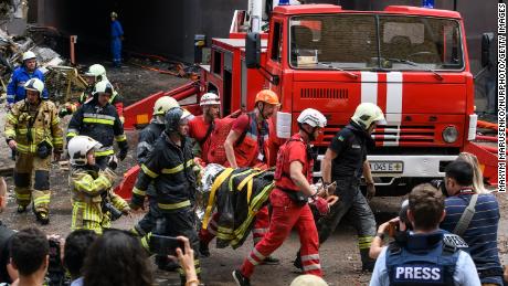 عمال الإنقاذ يخلون شخصًا من مبنى سكني دمر في غارة جوية روسية في منطقة شيفتشينكيفسكي في كييف في 26 يونيو 2022.
