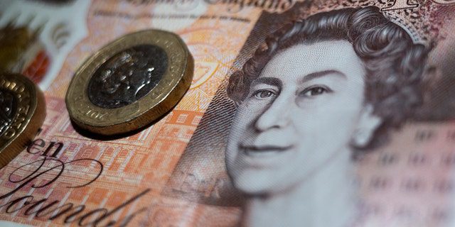 العملة البريطانية على شكل عملتين من فئة الجنيه الواحد موضوعة على قمة ورقة نقدية من فئة عشرة جنيهات من بنك إنجلترا تظهر صورة الملكة إليزابيث الثانية.