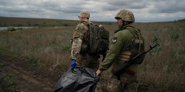 جنود الحرس الوطني الأوكراني يحملون حقيبة تحتوي على جثة جندي أوكراني في منطقة بالقرب من الحدود مع روسيا ، في منطقة خاركيف ، أوكرانيا ، الاثنين 19 سبتمبر 2022. في هذه العملية ، تم انتشال سبع جثث لجنود أوكرانيين مما كان ساحة المعركة في الأشهر الأخيرة. 