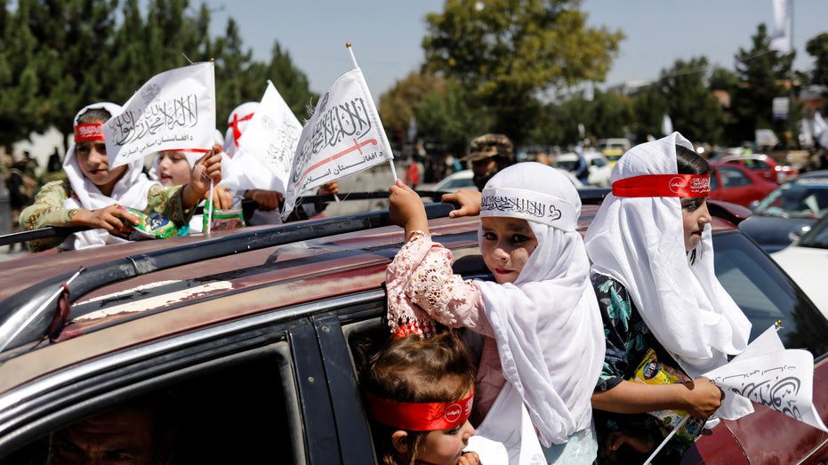 فتيات أفغانيات يحملن أعلام الإمارة الإسلامية أثناء مشاركتهن في الذكرى الأولى لانسحاب القوات الأمريكية من أفغانستان