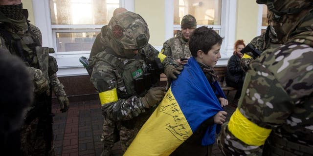 صبي يحمل علمه الوطني الأوكراني موقعة من قبل أفراد من الجيش الأوكراني ، 19 نوفمبر 2022 ، في خيرسون ، أوكرانيا.