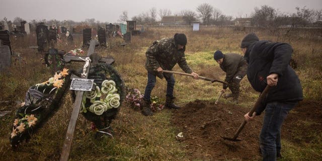 سكان ومسؤولون أوكرانيون يستخرجون جثة فتاة تبلغ من العمر 16 عامًا وسبعة رجال آخرين قتلوا على يد القوات الروسية ودُفنوا في بلدة برافدين بضواحي خيرسون في 29 نوفمبر 2022.